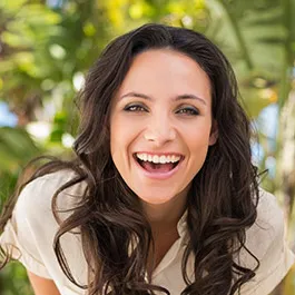 Woman with dark hair smiling outdoors