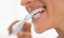 Profile nose-to-chin view of woman brushing teeth with electric brush