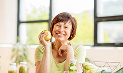 Woman with dental implants in Frisco holding an apple