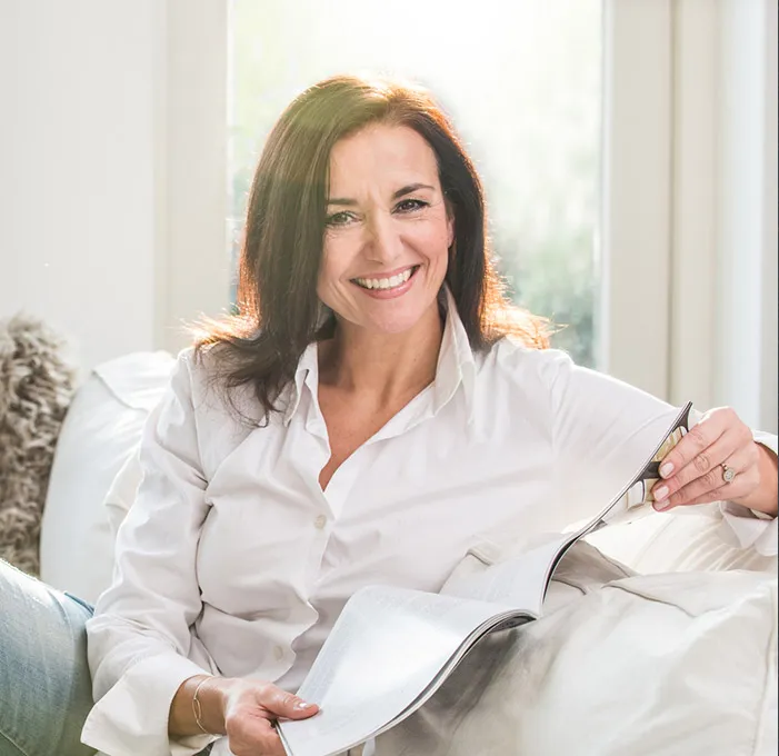 Woman in white shirt reading a magazine by window