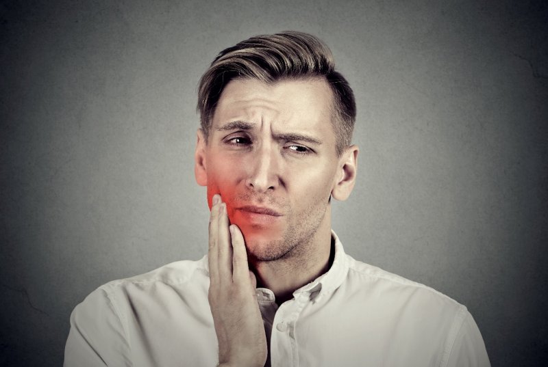 A man holding his mouth in pain.