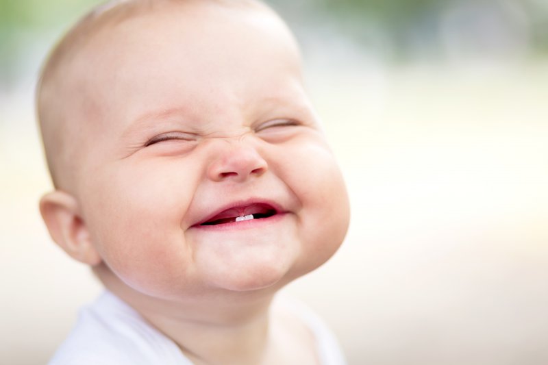 A smiling baby with a tongue tie.