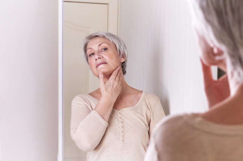 Woman examining her gum disease and facial shape in Frisco