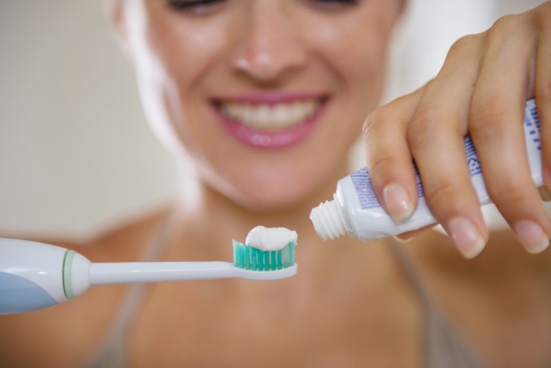 Woman with healthy gums in Frisco applying toothpaste to toothbrush