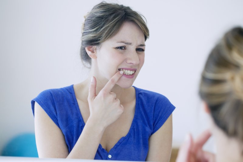 Woman examining her gingivitis in Frisco in mirror