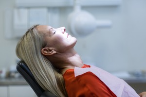 Female periodontal patient in red shirt relaxing in treatment chair